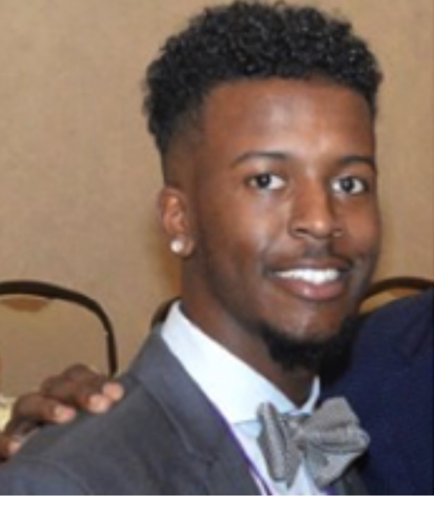 A man in a suit and bow tie posing for the camera.